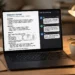 Laptop on a desk showing an AI-generated research report with summary, comparison table and footnotes beside a chat window