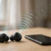 Wireless earbuds on a desk next to a smartphone, with a disrupted signal wave illustrating Bluetooth dropouts