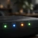 Close-up of a home router's front panel with glowing green, blue and amber LED lights labelled Power, Internet, Wi-Fi and LAN