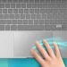 Top-down illustration of a laptop with a hand swiping three fingers across the trackpad, with glowing motion trails showing the gesture