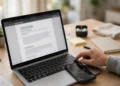 Person pressing keyboard screenshot shortcuts on a laptop with a smartphone showing a screen-capture frame beside it