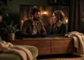 A modern flat-screen TV in a dim living room showing a cinematic period-drama scene.
